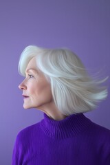 An older woman with white hair, wearing a purple sweater, in profile, with wind in her short blonde bob haircut.
