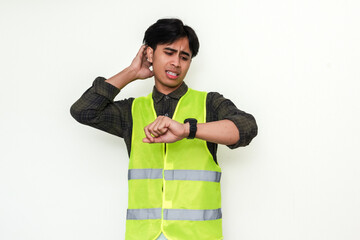 Portrait of a confused Asian construction worker looking at his watch, isolated on white...