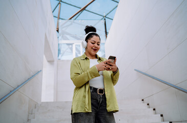 Woman navigates her smartphone while wearing wireless headphones, engaging in digital content....