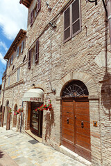 Warm sunlight illuminates the rustic charm of Assisi, Umbria highlighting its medieval buildings and a quaint market. Shop nestled in the historic street of Assisi.