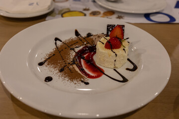 Dessert plate featuring whipped cream, strawberries, and chocolate sauce artfully arranged.