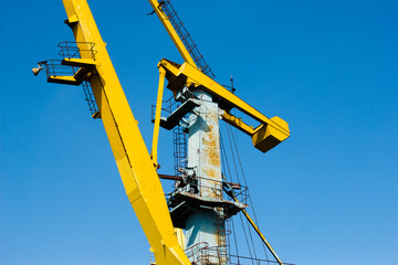 Lone rusty crane against clear sky. Minimalism, geometry of metal structures, contrast of decay and...