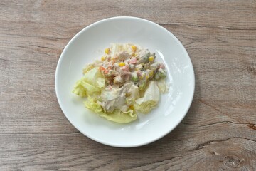mashed tuna with corn and garden pea couple cabbage vegetable salad dressing cream sauce on plate