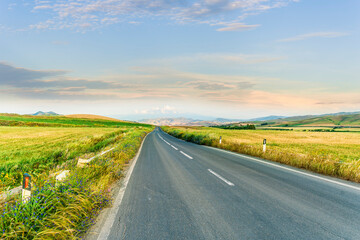 beautiful landscape of long road to amazing mountain scene from a green summer fields and hills....