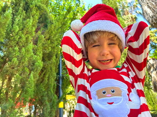 Little preschool boy in Santa Claus costume on playground, in kindergarten at resort. Christmas in...