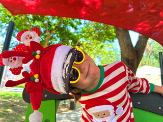 Little preschool boy in Santa Claus costume on playground, in kindergarten at resort. Christmas in...