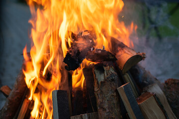 Pile of wood with a fire burning in the middle. The fire is orange and the wood is charred.