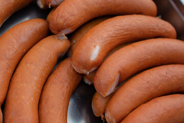 Close-up of raw smoked sausages arranged in a metal tray, ready for grilling or cooking....