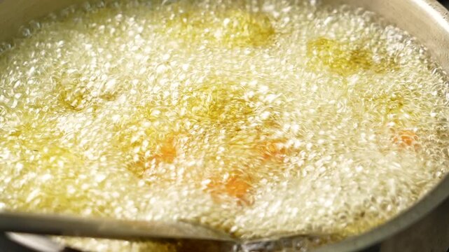 Marinated cubes of boneless fish getting deep fried in hot oil