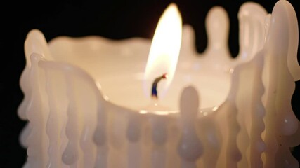 Close up of a lit white candle with dripping wax against a dark black background view detail - Powered by Adobe