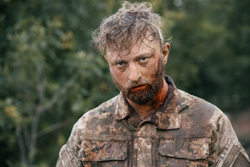 Close-up portrait of a wounded soldier covered in blood during combat. The soldier's face is...
