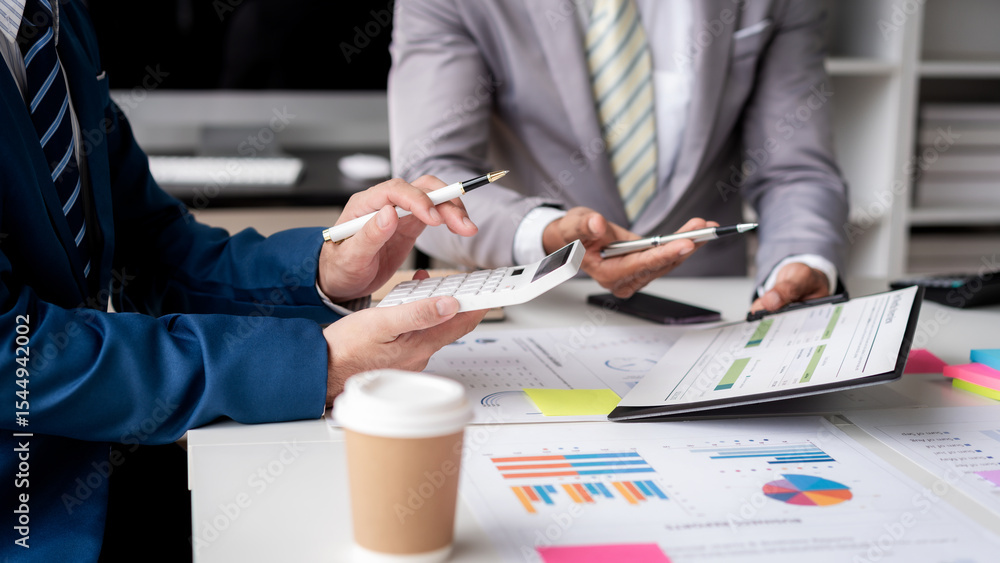 Poster Two men are sitting at a table with a calculator and a stack of papers