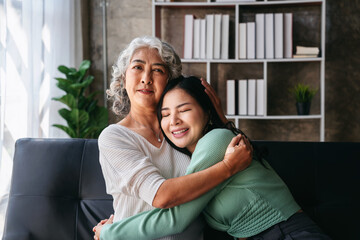 Affectionate Asian Women: Mother Daughter Embrace on Couch, Family Love and Connection,...