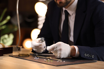 Appraiser with loupe evaluating ring at table indoors, closeup