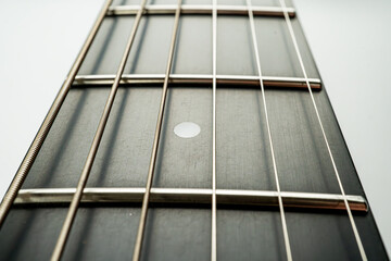 Close-up image of an acoustic guitars fretboard and bridge, emphasizing the wooden texture and...