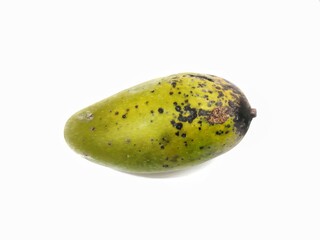 A whole ripe mango with green skin and black spots on a white background