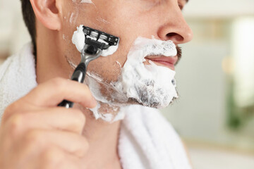 Man shaving with razor at home, closeup