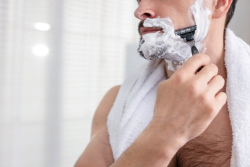 Man shaving with razor at home, closeup. Space for text