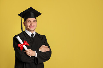 Happy student with diploma after graduation on yellow background. Space for text