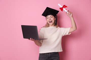 Happy student with diploma and laptop after graduation on pink background