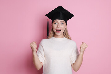 Happy student after graduation on pink background