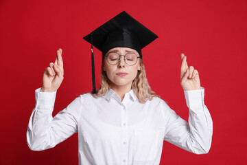 Emotional student crossing fingers on red background. Hope for good graduation