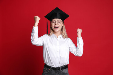 Happy student after graduation on red background