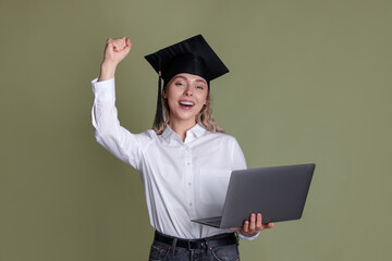 Happy student with laptop after graduation on green background