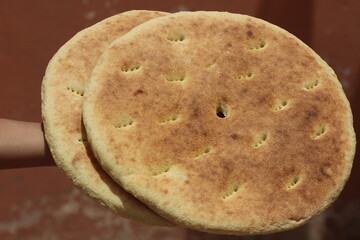 Hand holding moroccan bread known as khobz, Traditional Moroccan Bread