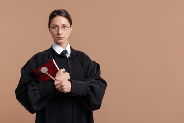 Judge with mallet and book on light brown background, space for text