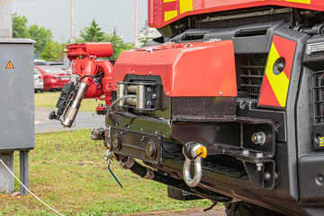 Red fire truck with rescue equipment on grassy area under overcast sky, water cannonnozzle,...