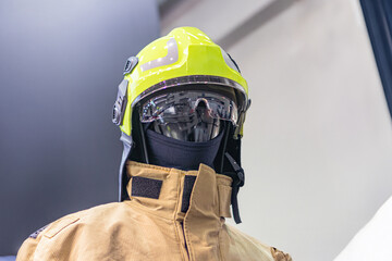 Image of a firefighters suit against a light background, featuring a yellow helmet with visor and...