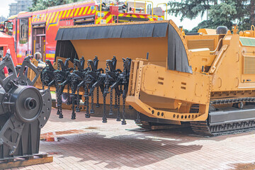Yellow and black excavator with hydraulic arms on construction site with paving stones, possibly...