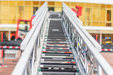 Red ladder truck with safety handrails, extended aerial device, multiple compartments, daylight lighting, straightforward style