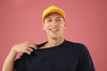 Young man in stylish baseball hat on pink background
