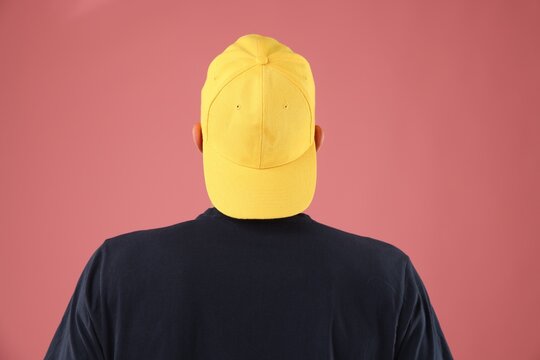Young man in stylish baseball hat on pink background, back view - Powered by Adobe