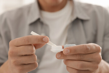 Man taking contact lens out of case at home, closeup