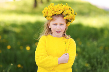 Cute little girl with beautiful flower wearing wreath of dandelions in park