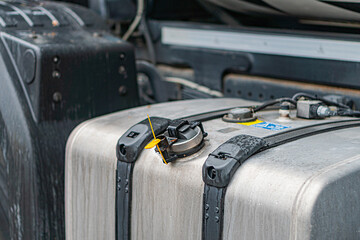 Outdoor image of a cargo container, rectangular in shape and metal, securely fastened to a vehicle Has two yellow handles on sides for manual movement or lifting The background is indistinct, sugge
