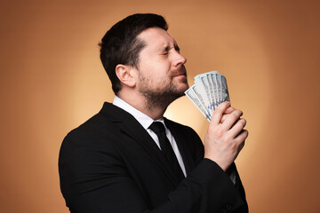 Greedy banker with dollar banknotes on golden background