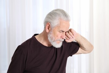 Senior man suffering from eyestrain at home