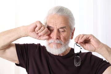 Senior man with glasses suffering from eyestrain at home