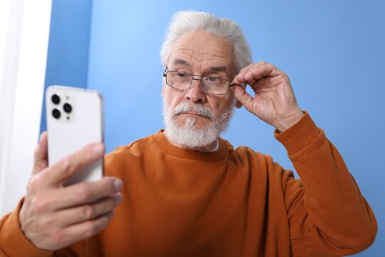 Senior man with vision problem using smartphone at home