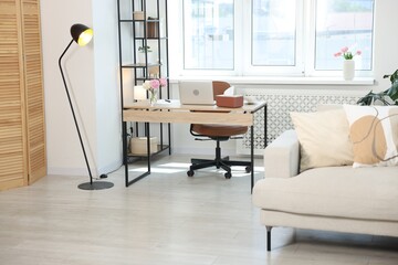 Desk with laptop in stylish room. Interior design