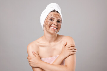 Smiling woman with body scrub on her face against grey background