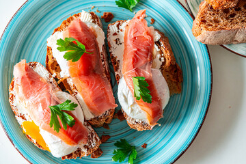 Toast with poached egg, cream cheese and red fish on a blue plate. Delicious and healthy breakfast. Top view