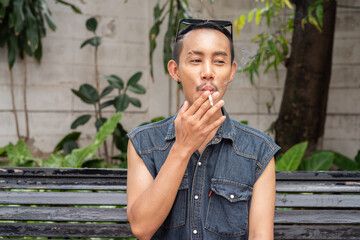 Fototapeta premium Stylish gay man sitting outdoors and smoking cigarette