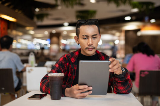 Portrait of nonbinary genderfluid young Asian gay man using digital tablet computer