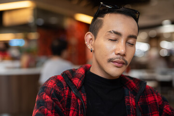 Portrait of nonbinary genderfluid young Asian gay man relaxing with eyes closed