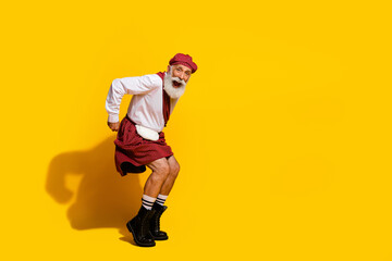 Elderly man in traditional Scottish kilt expressing joy against a vibrant yellow background